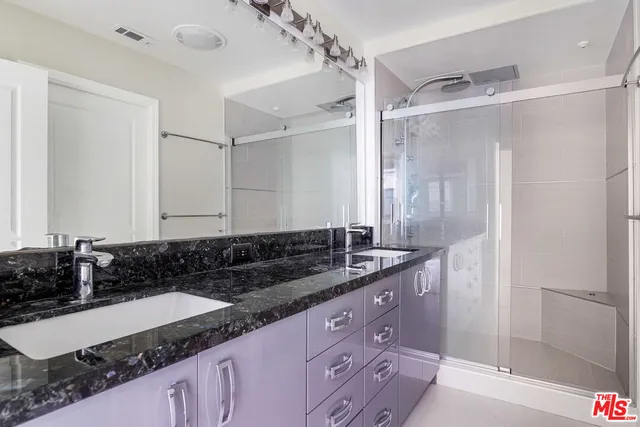 a bathroom with a granite countertop sink a mirror and a shower