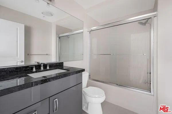 a bathroom with a granite countertop sink toilet and shower