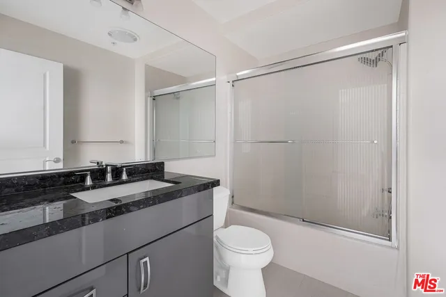 a bathroom with a granite countertop sink toilet and shower