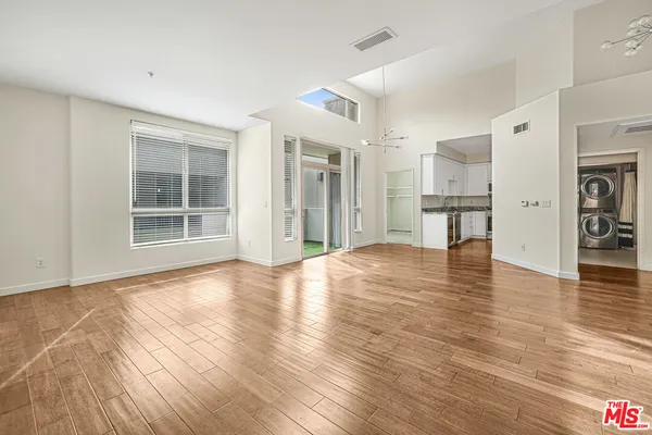a view of an empty room with window and wooden floor