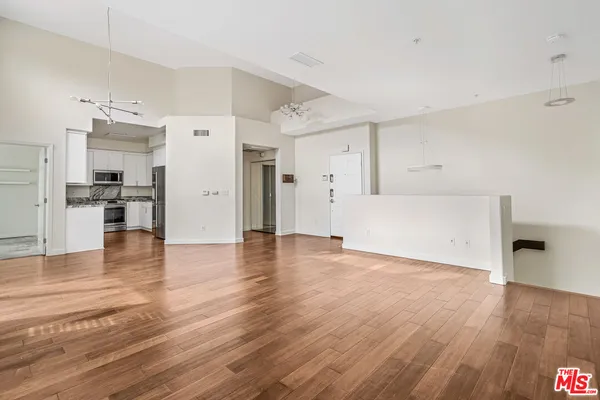 a view of a kitchen with a fridge and wooden floor