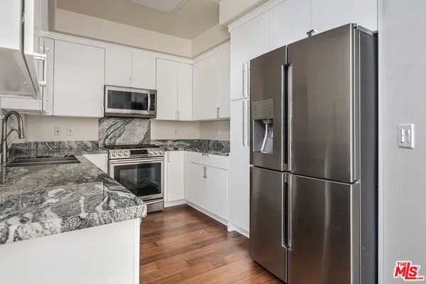 a kitchen with stainless steel appliances granite countertop a refrigerator stove and microwave