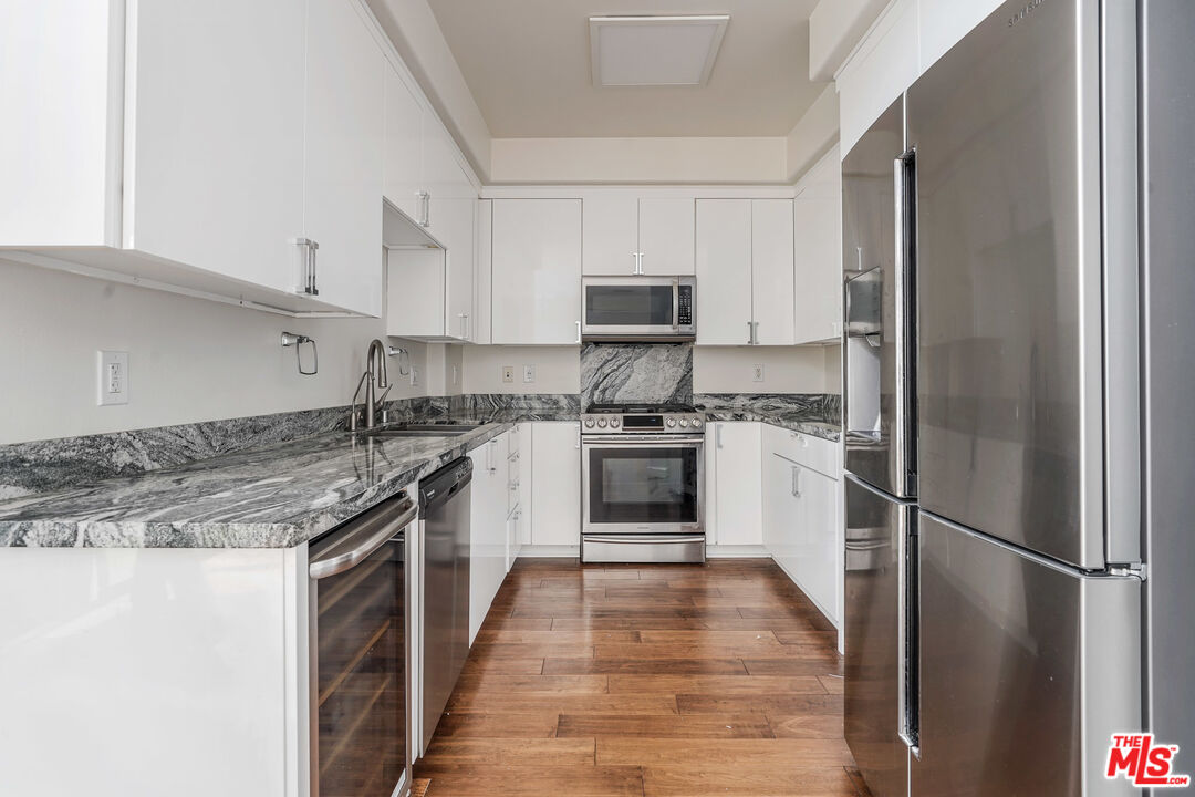 13044 Pacific Promenade, Unit 417 Playa Vista, CA 90094 - Photo 8 of 31 a kitchen with stainless steel appliances granite countertop a refrigerator a stove a sink and white cabinets
