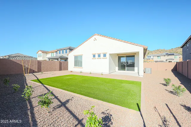 a view of a white house next to a yard with big trees