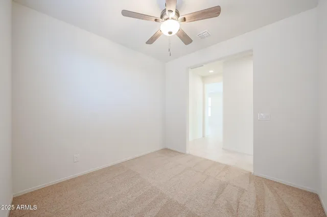 an empty room with a chandelier fan and windows
