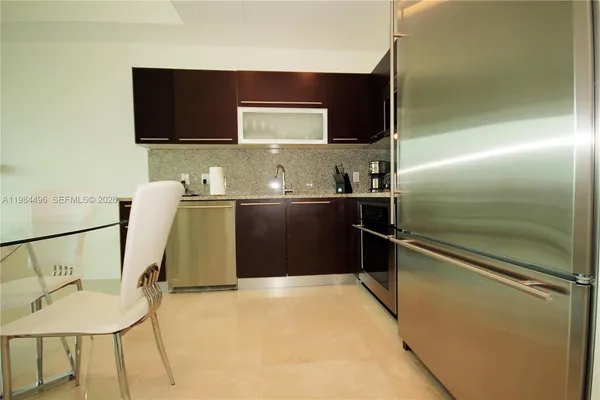 a kitchen with stainless steel appliances kitchen island granite countertop a refrigerator and a stove top oven