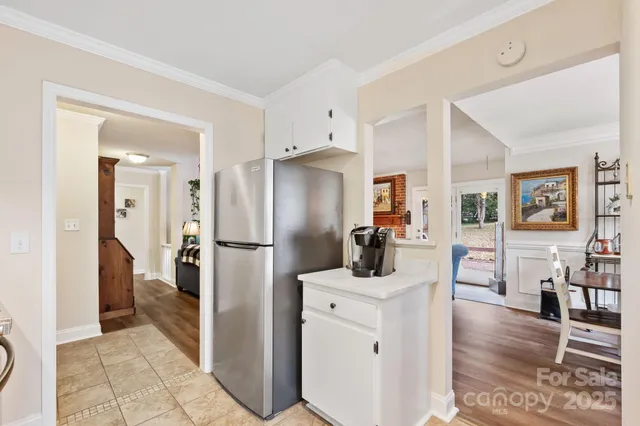 a kitchen with a refrigerator a sink dishwasher a dining table and chairs with wooden floor