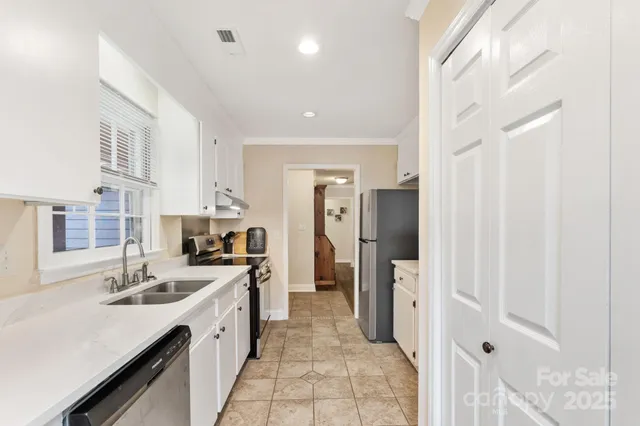 a large white kitchen with lot of cabinets and sink