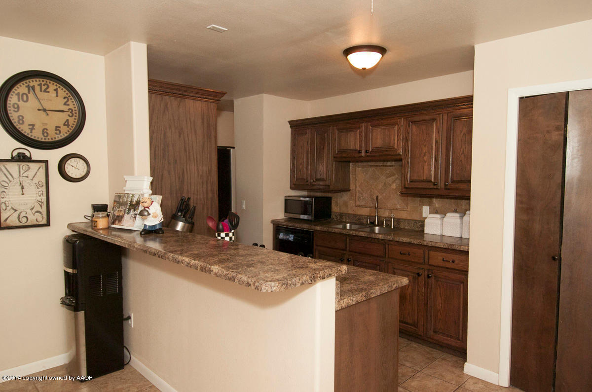 2607 Darrell Avenue Amarillo, TX 79110 - Photo 6 of 28 a kitchen with kitchen island granite countertop wooden cabinets and a refrigerator