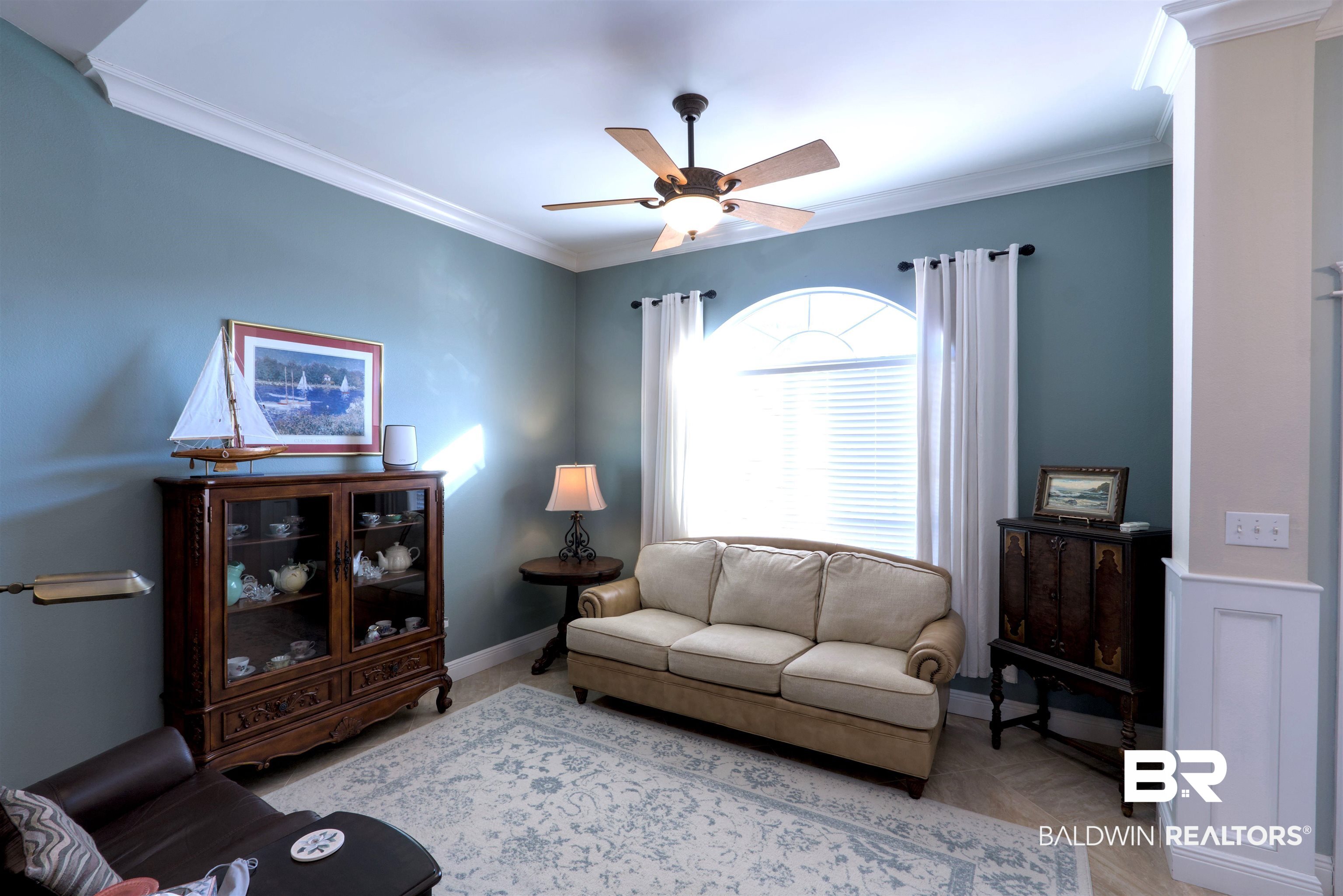 373 Collinwood Loop Foley, AL 36535 - Photo 7 of 49 Arched window with blinds and white drapes, crown molding, ceiling fan with light fixture, tile flooring, and decorative wainscoting