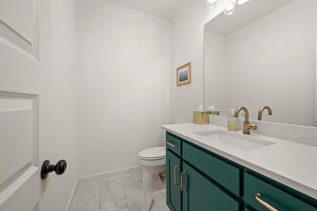a bathroom with a granite countertop sink a toilet and a mirror