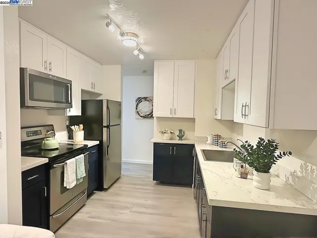 a kitchen with stainless steel appliances granite countertop a sink stove refrigerator and cabinets