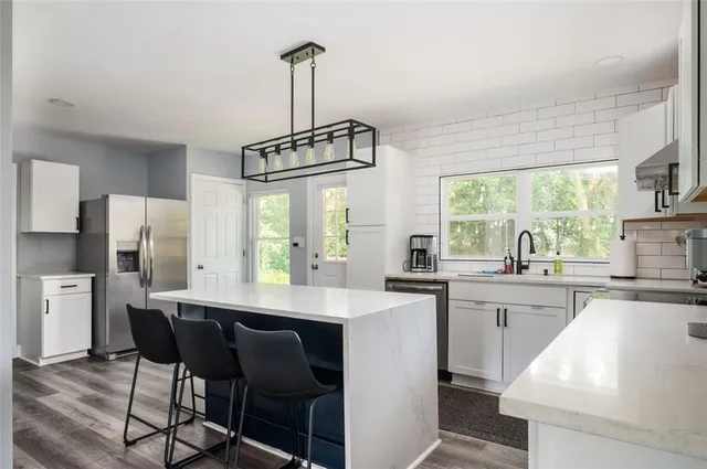 a kitchen with stainless steel appliances a kitchen island a stove a table and chairs in it