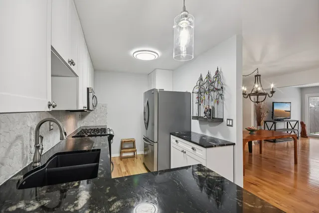 a kitchen with stainless steel appliances granite countertop a refrigerator a stove and a sink with granite countertops