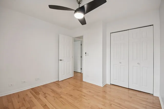 an empty room with wooden floor ceiling fan and windows