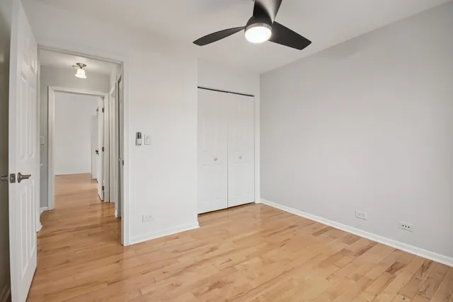 an empty room with wooden floor closet and ceiling fan