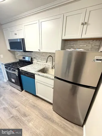 a kitchen with stainless steel appliances granite countertop a refrigerator sink stove and white cabinets