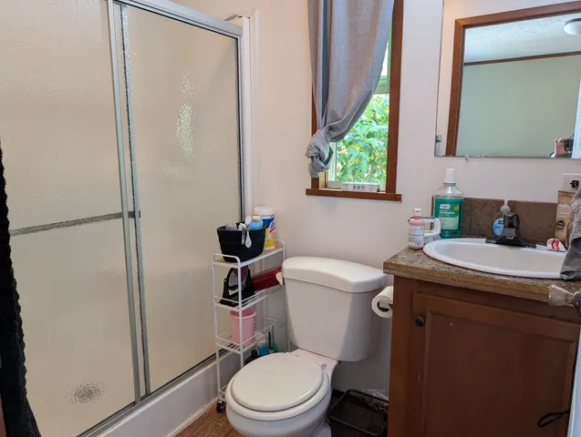 a bathroom with a granite countertop toilet a sink and a shower