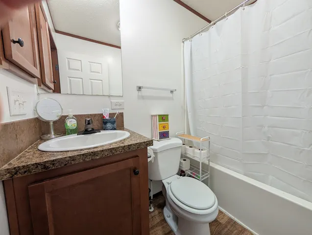 a bathroom with a granite countertop toilet sink and mirror