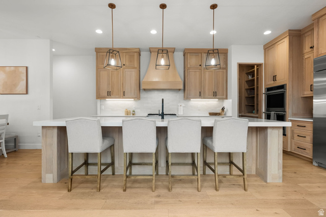 5354 Cyan Lane St. George, UT 84790 - Photo 5 of 45 Kitchen with a kitchen bar, a spacious island, hanging light fixtures, and light wood-style flooring