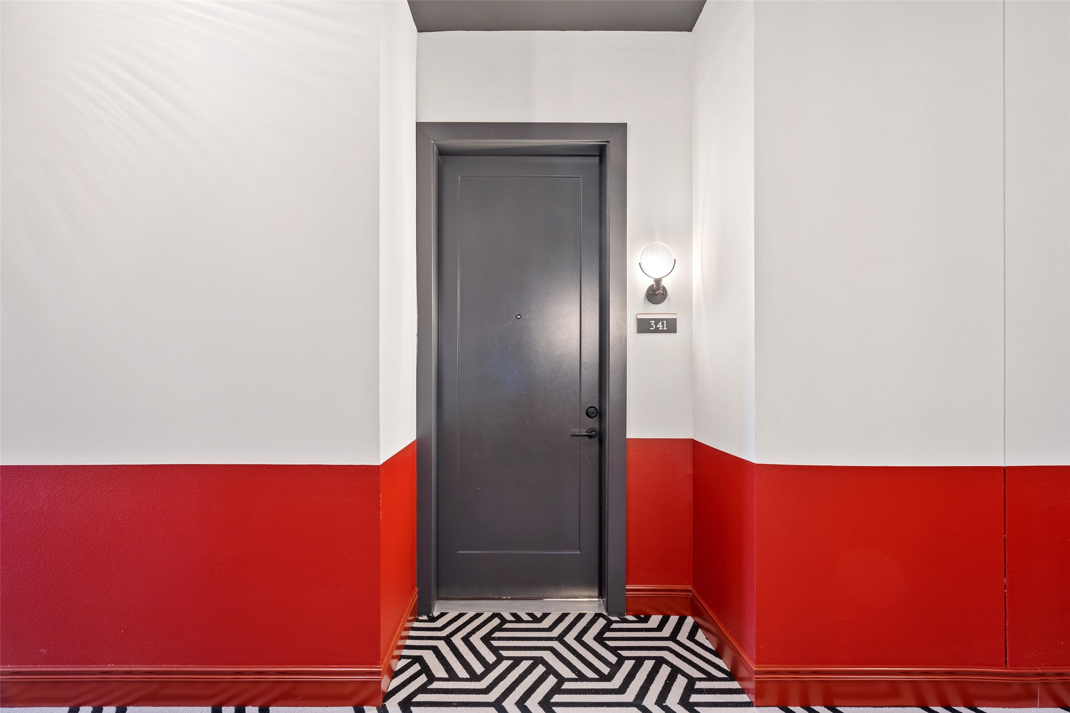 4510 Terry-O Lane, Unit 341 Austin, TX 78745 - Photo 2 of 40 The property entrance features a dark gray door, a contemporary wall sconce, and a geometric pattern floor mat