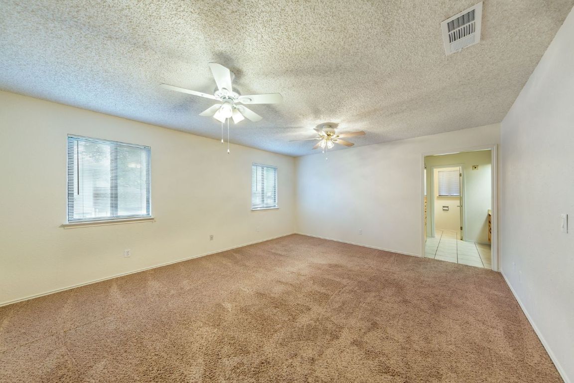 8501 Fathom Circle, Unit A Austin, TX 78750 - Photo 17 of 30 an empty room with a chandelier fan and windows