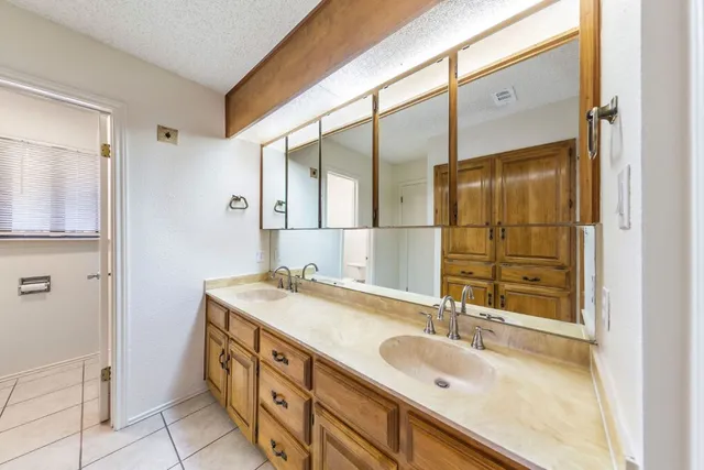 a bathroom with a granite countertop double vanity sink and mirror