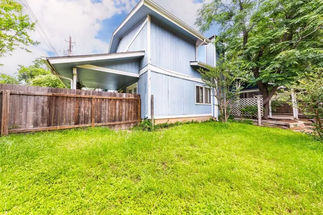 a view of a house with backyard and wooden fence