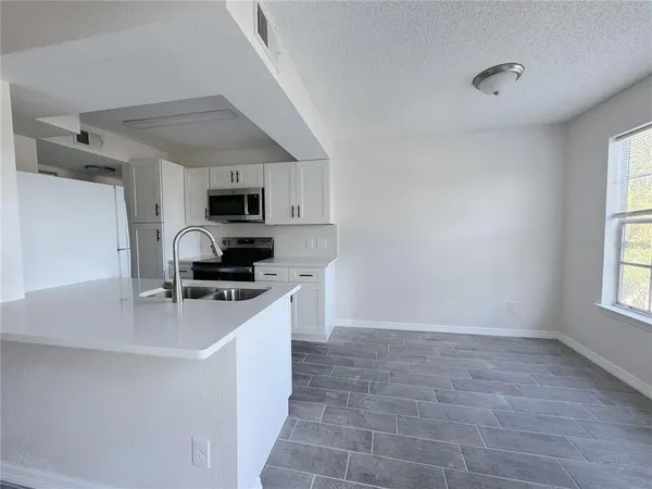 a kitchen with a sink a microwave and cabinets