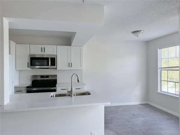 a kitchen with stainless steel appliances a stove a microwave and white cabinets