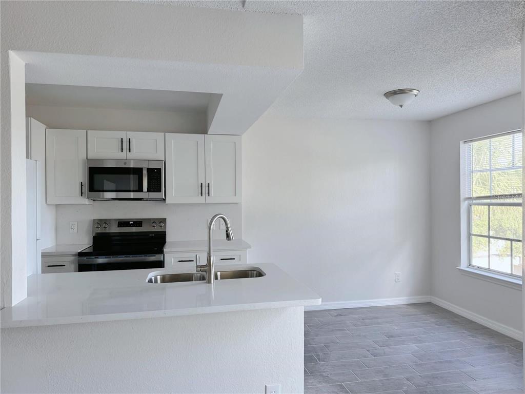 1013 South Hiawassee Road, Unit 3635 Orlando, FL 32835 - Photo 6 of 18 a kitchen with stainless steel appliances a stove a microwave and white cabinets