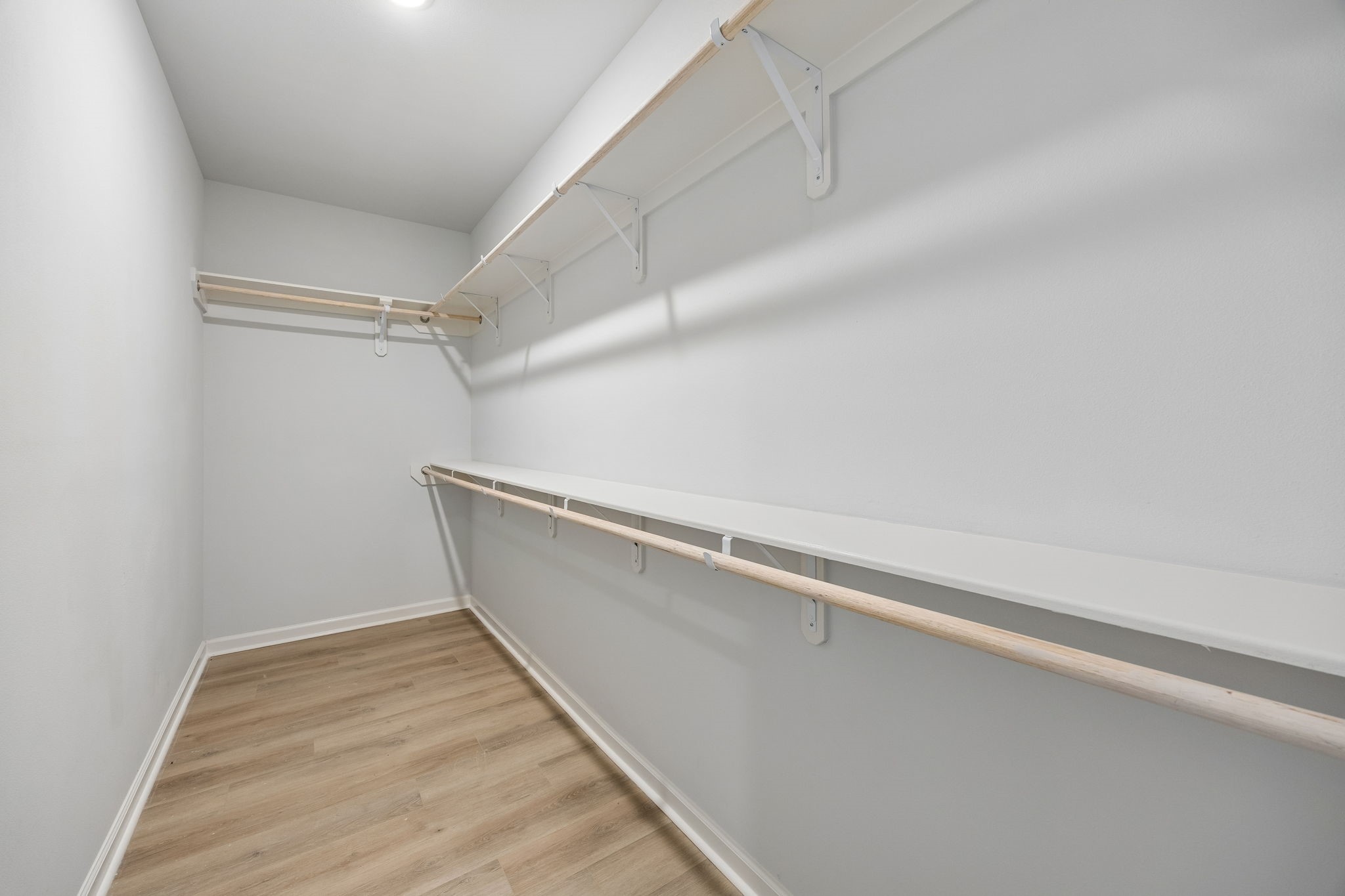 10902 Bonfire Trail Beasley, TX 77417 - Photo 15 of 36 This is a spacious walk-in closet with light vinyl plank flooring, white walls, and multiple shelves and hanging rods for ample storage.