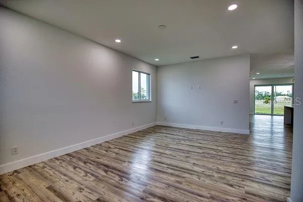 a view of an empty room with wooden floor and a window
