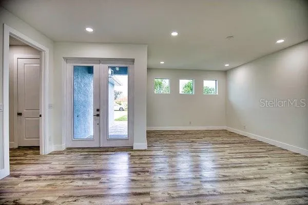 a kitchen with stainless steel appliances granite countertop a refrigerator a sink dishwasher a stove and white cabinets with wooden floor