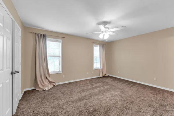 an empty room with windows and ceiling fan
