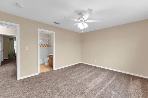 an empty room with chandelier fan and windows