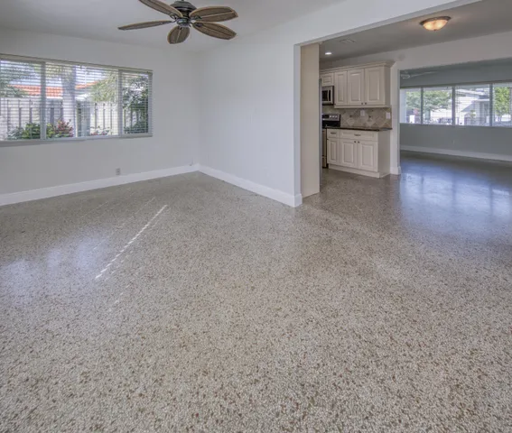 a view of an empty room with a kitchen view and window
