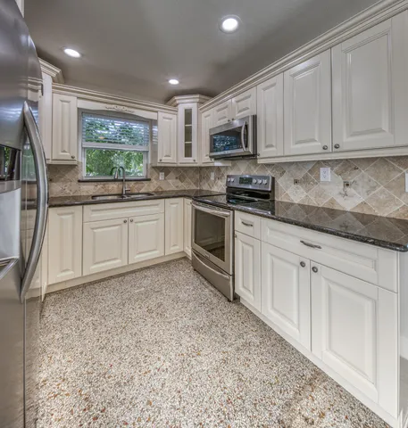 a kitchen with stainless steel appliances granite countertop a stove a sink and a microwave