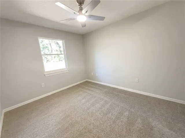 an empty room with a window and a fan