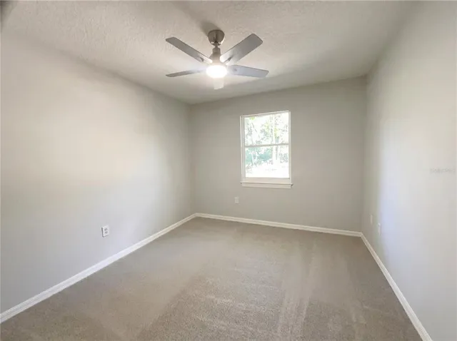 an empty room with windows and fan