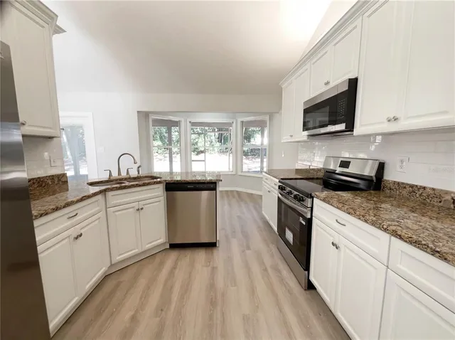 a kitchen with sink a microwave and cabinets