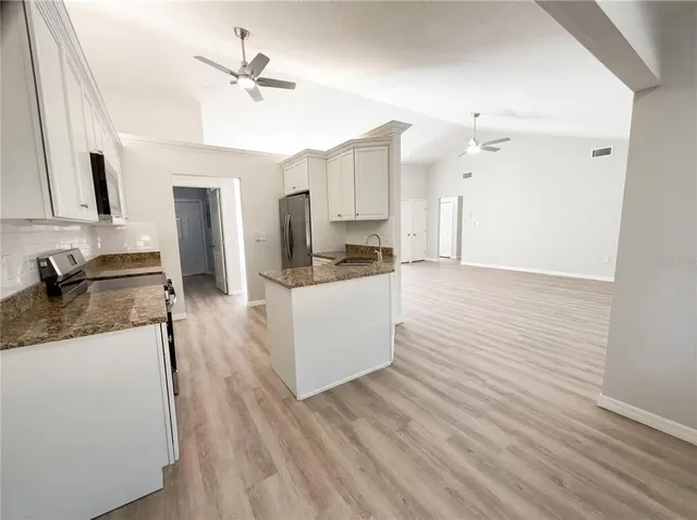 a kitchen with granite countertop a sink stainless steel appliances and cabinets