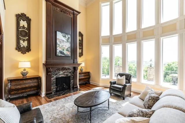 a living room with furniture a fireplace and large windows