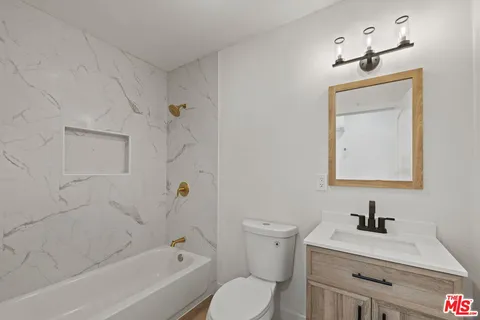 a bathroom with a bathtub sink vanity mirror and toilet