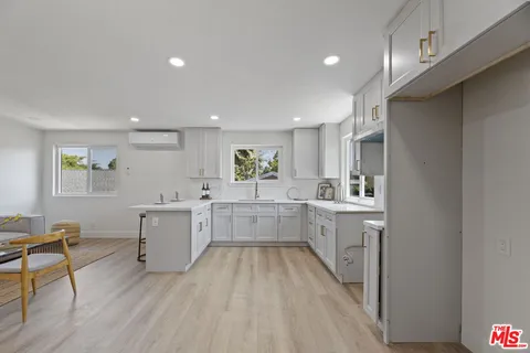 a large white kitchen with lots of counter space wooden floor and stainless steel appliances