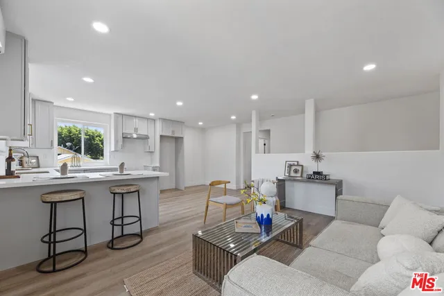 a living room with furniture kitchen view and a wooden floor