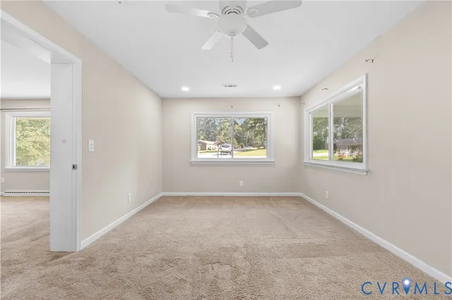an empty room with windows and ceiling fan