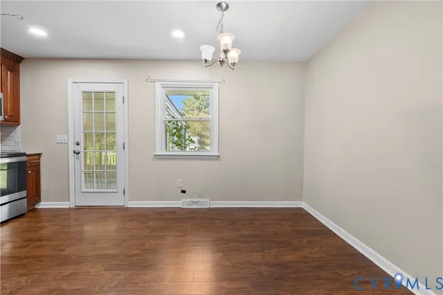 an empty room with wooden floor cabinet and windows
