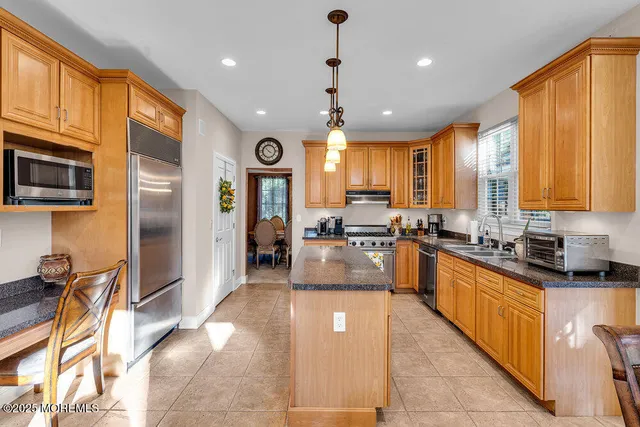 a large kitchen with stainless steel appliances kitchen island granite countertop a sink counter space and a view of living room