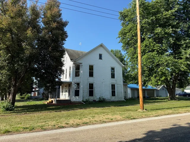 a view of a white house with a large tree and a yard